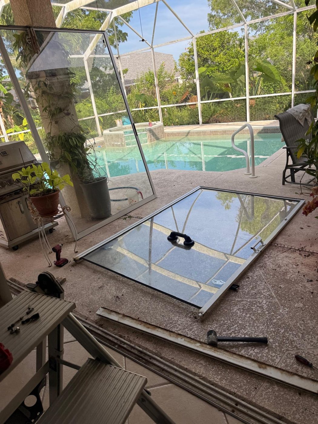 Sliding glass door panel lifted out onto a Florida pool deck during an alignment and tune-up