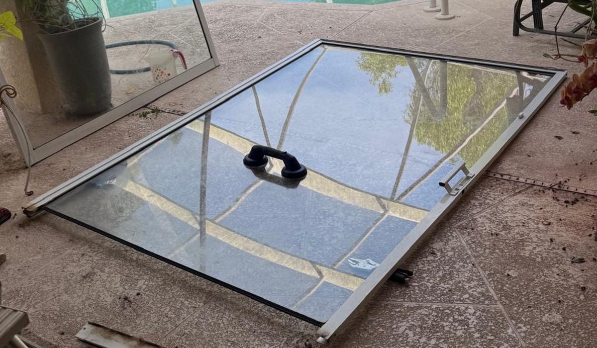 Sliding glass door panel lifted out of its frame and laid flat for roller replacement